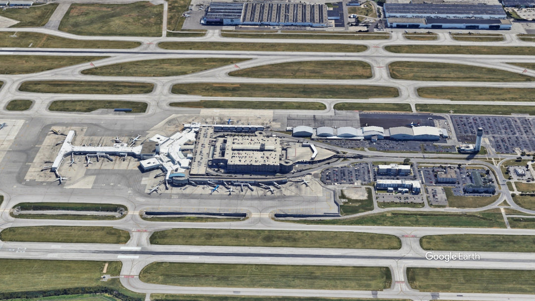 Aerial view of John Glenn Columbus International Airport (CMH) in Columbus, Ohio, showing the terminal, runways, taxiways, aircraft gates, and control tower.