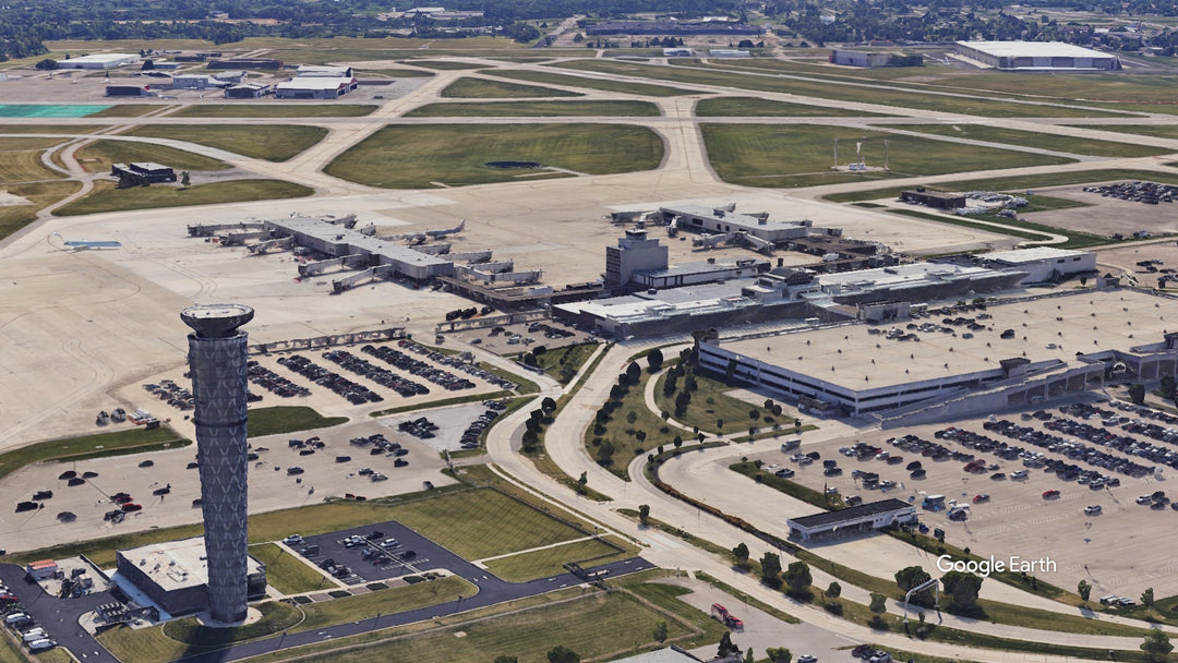 Aerial view of James M. Cox Dayton International Airport (DAY) in Dayton, Ohio, showing the control tower, terminal, concourses, gates, and airport runways.