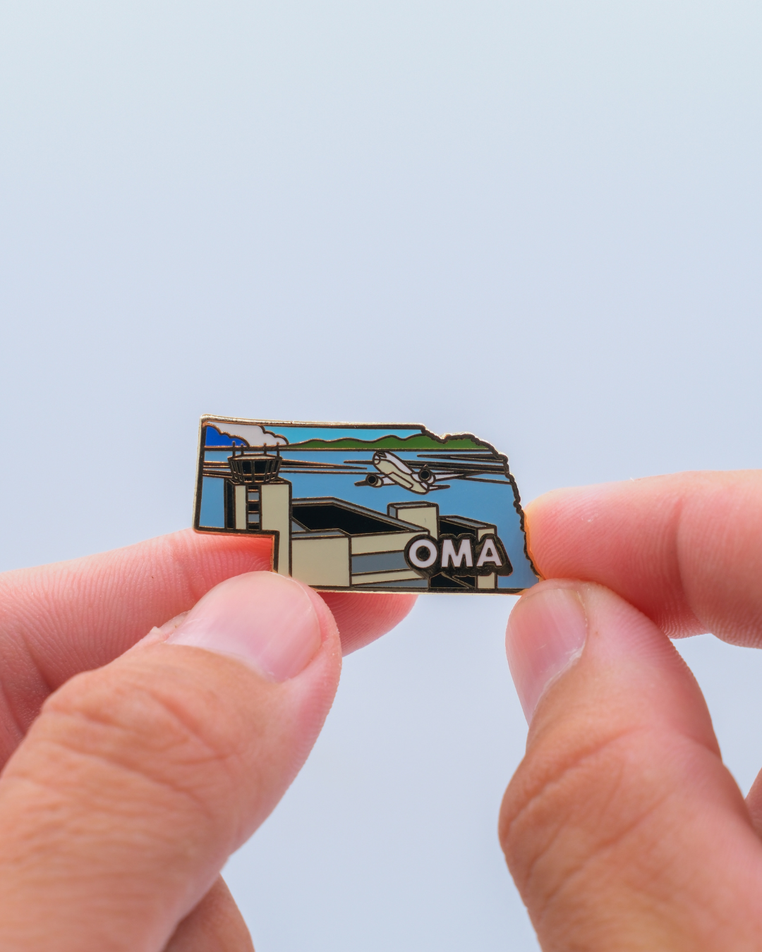 OMA airport pin for Eppley Airfield, held by hand.
