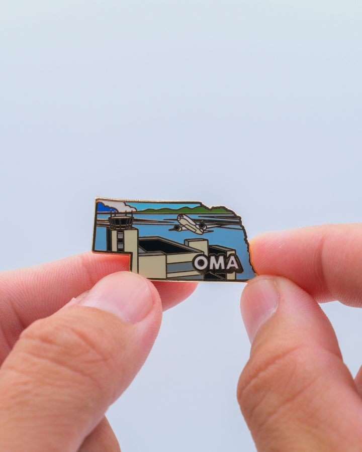 OMA airport pin for Eppley Airfield, held by hand.